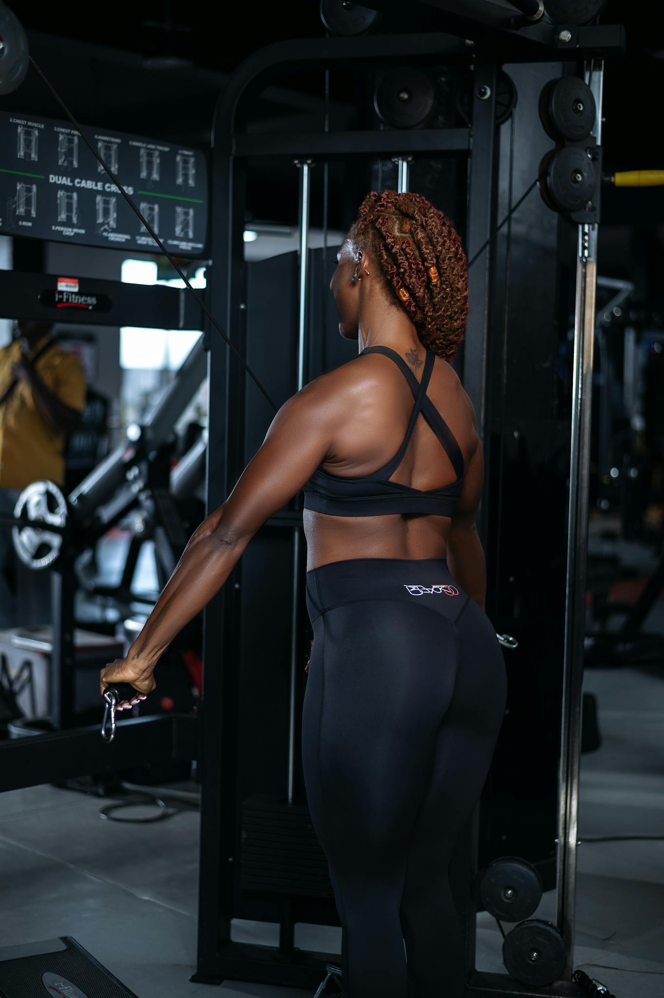 Athletic woman working out in a modern gym with fitness equipment, emphasizing strength and determination.