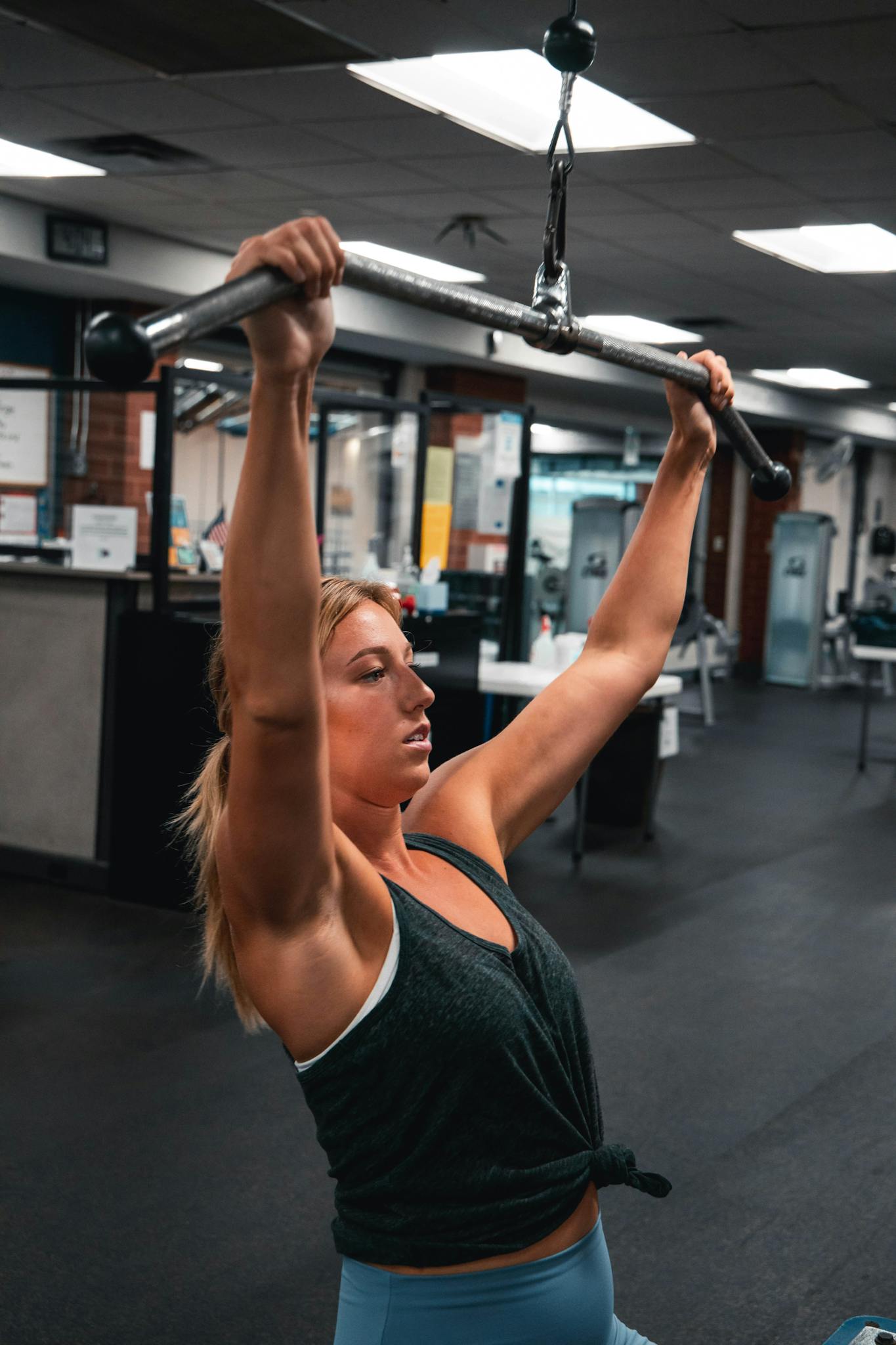 Woman working out on exercise machine in a gym environment, showcasing strength and fitness.